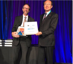 Marc Nantel, PhD receiving the Gold Award of Excellence from WFCP deputy chair Zong Wa on stage at WFCP 2018 World Congress in Melbourne, Australia.