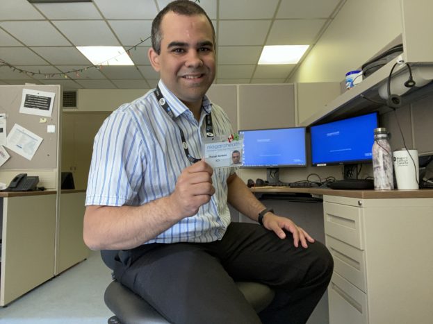 Rafael Almeida sitting at his desk in his new position within Niagara healthcare as a systems administrator.