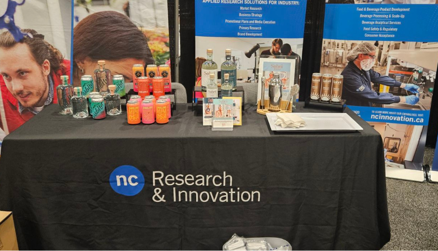 Research and Innovation's display booth with food and beverage products and promotional items at DiscoveryX 2024 in Toronto.