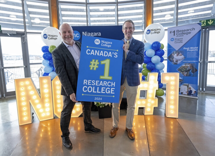 President Sean Kennedy and Marc Nantel holding a sign declaring Niagara College as #1 research college.