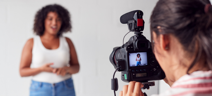 http://Videographer%20with%20camera%20pointed%20at%20woman%20who%20is%20speaking