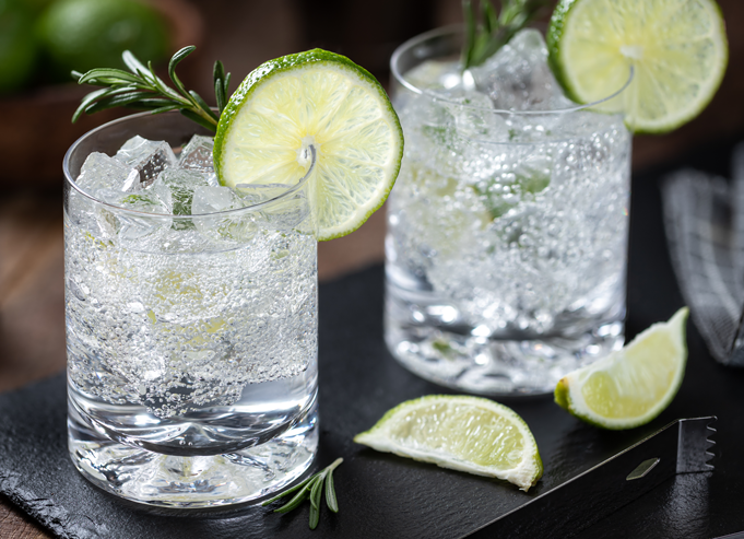 Carbonated beverages in short glasses on ice with wedges of lime.
